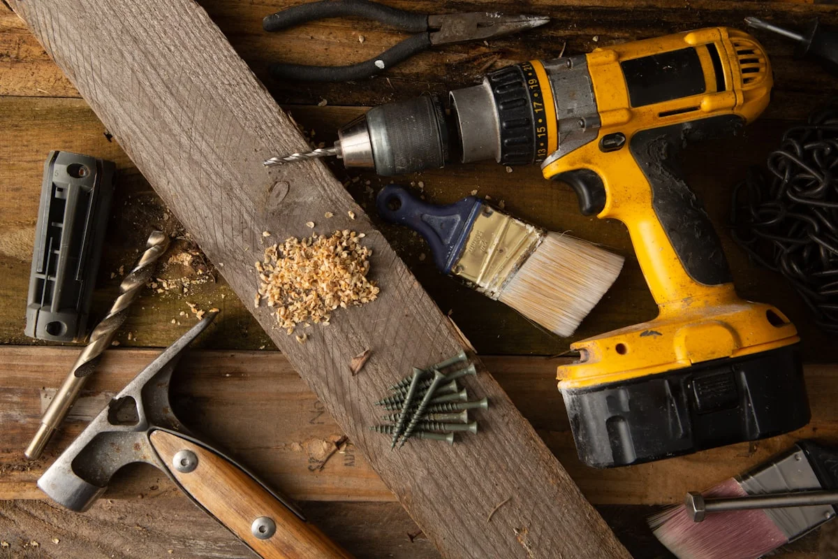 easy DIY projects for a beginner woodworker - A variety of tools, including a hammer and cordless drill, sit on top of a table made of wood boards.
