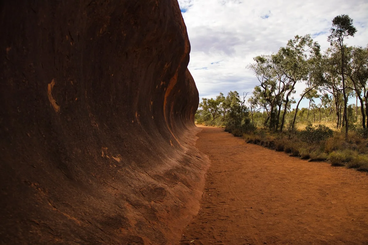 A backpacker on the Overland Track in Tasmania, walking across a wooden boardwalk with Cradle Mountain in the background