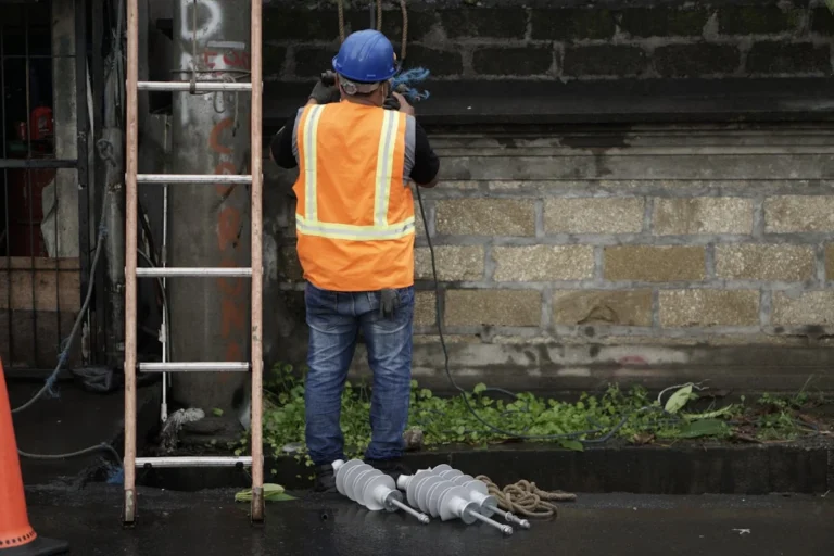 workers compensation claim help for injured workers — Worker with safety helmet and orange safety vest from the back,